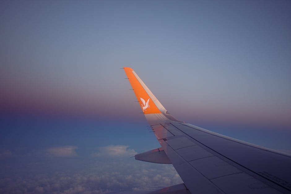 A serene view of an airplane wing soaring over clouds during sunset.