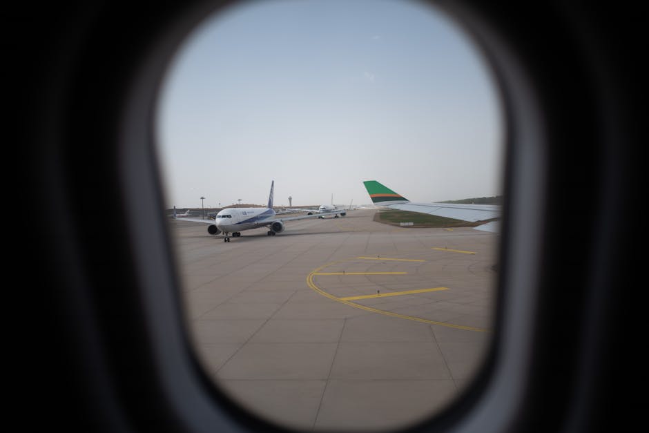 Airplane seen through a window, parked on the airport runway, capturing a travel moment.