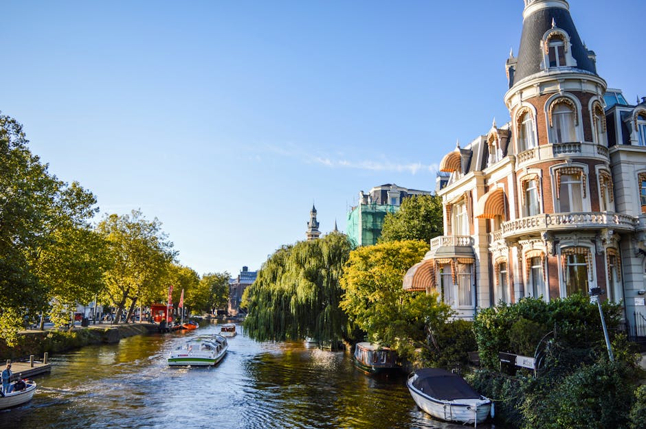 Picturesque view of Amsterdam canal with historical architecture and boats on a sunny day.