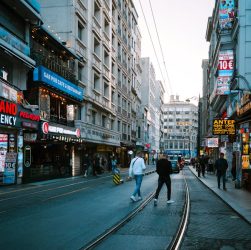 Vibrant street scene in Istanbul featuring shops, people, and tram tracks under a clear sky.