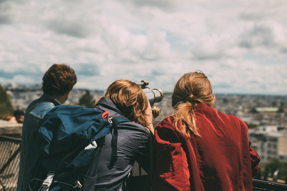 A group of young tourists exploring Paris views through a telescope during the day.